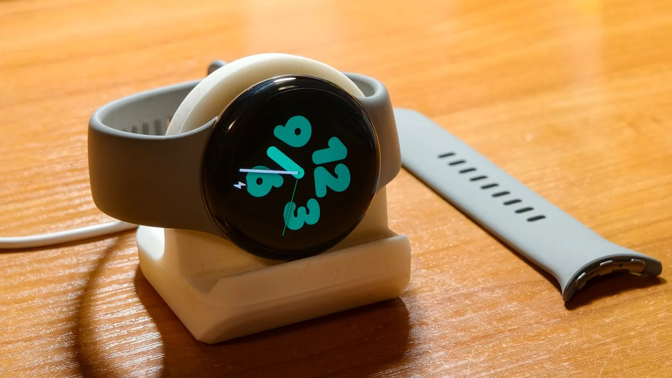Smartwatch on a charging dock with the always-on display showing the time