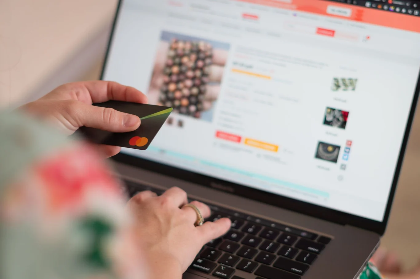 Person holding a credit card while browsing an online store on a laptop