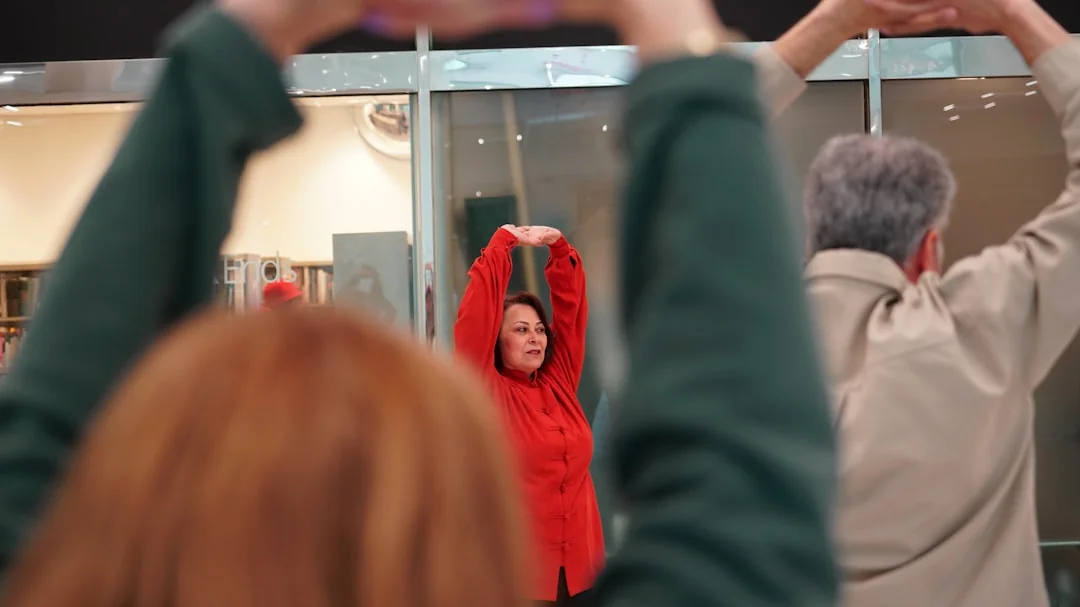 People stretching with arms raised in a mirrored fitness studio