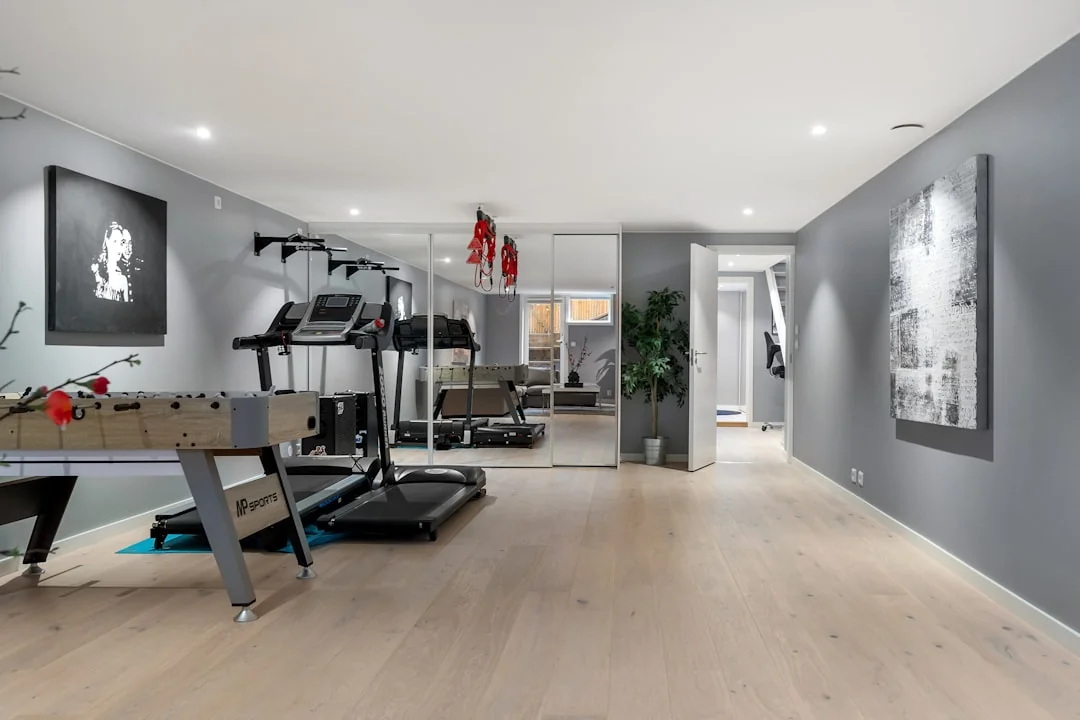 Home gym with a wall of mirrors reflecting a treadmill and workout equipment