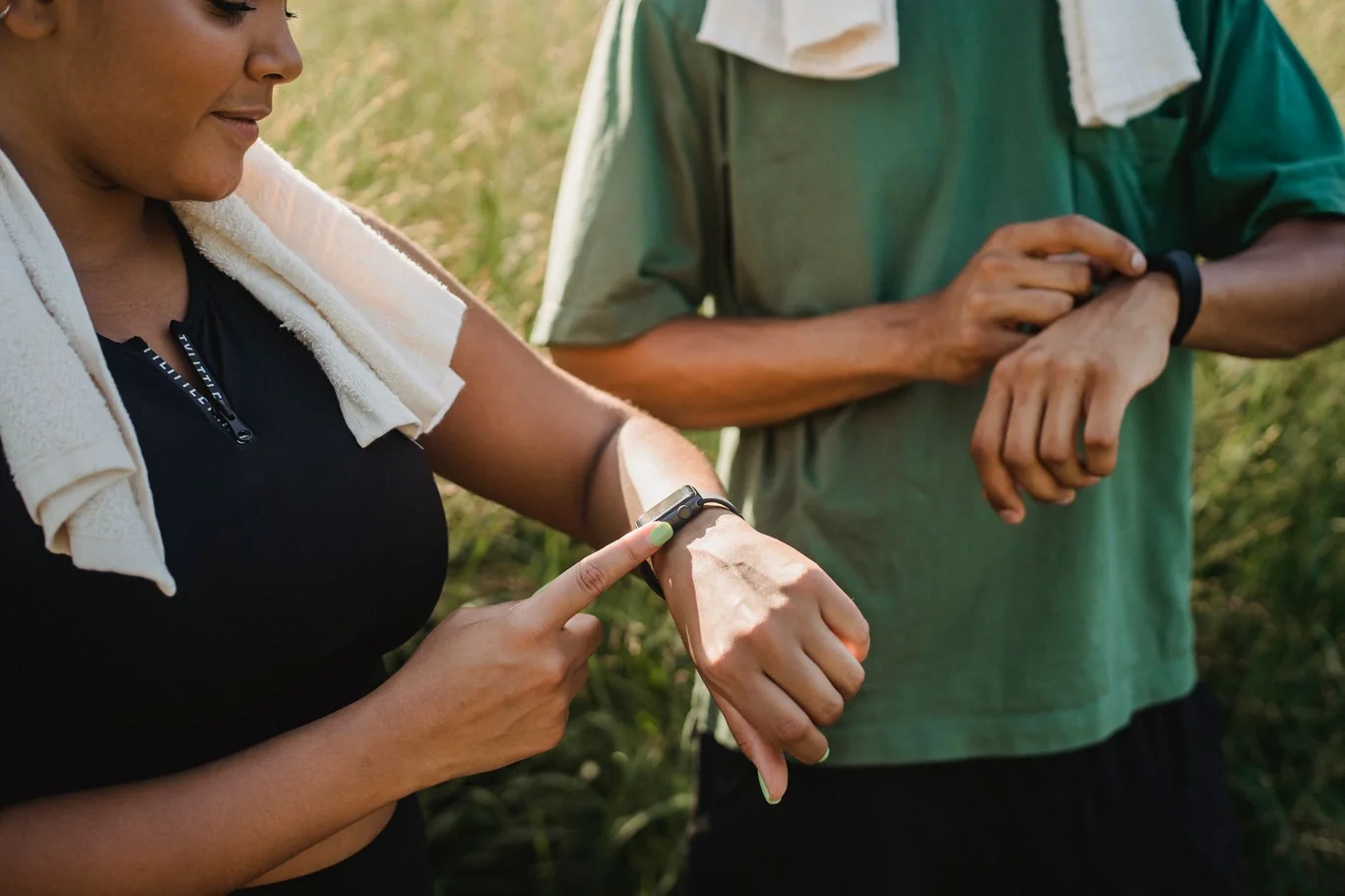 Woman outdoors pointing at a fitness tracker on her wrist after a workout
