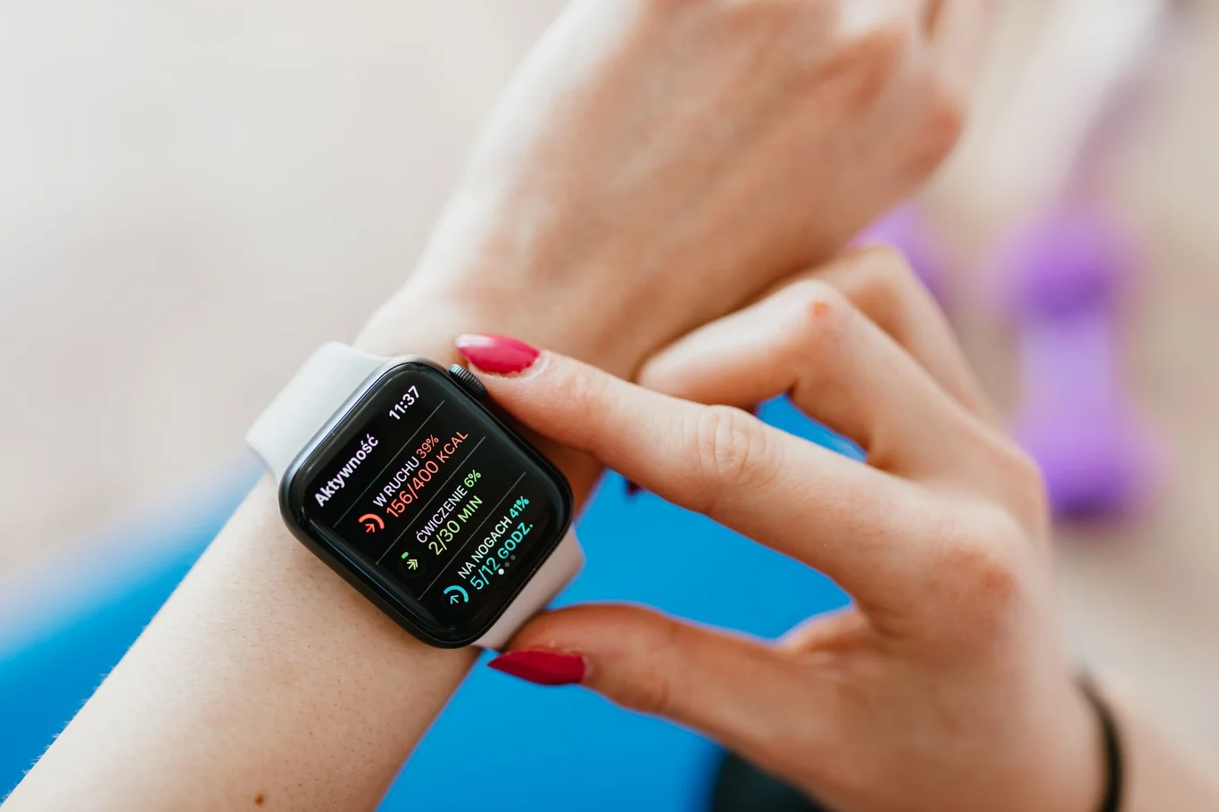 Woman checking calorie burn and exercise minutes on an Apple Watch beside pink dumbbells