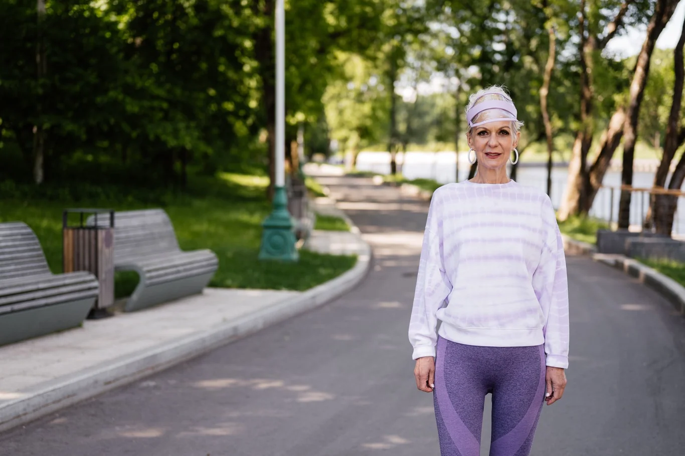 Older woman in athletic wear walking along a sunny park path