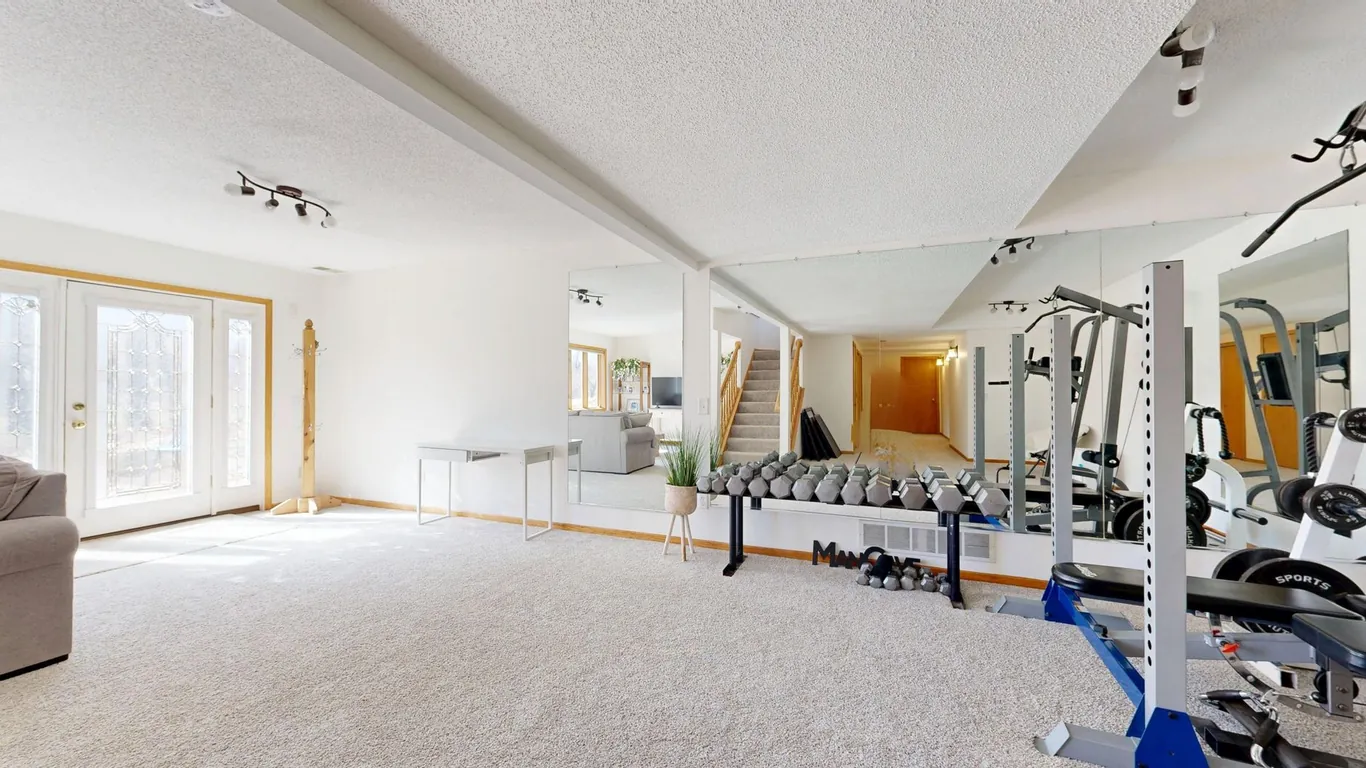 Home basement gym with a large wall mirror and rack of dumbbells