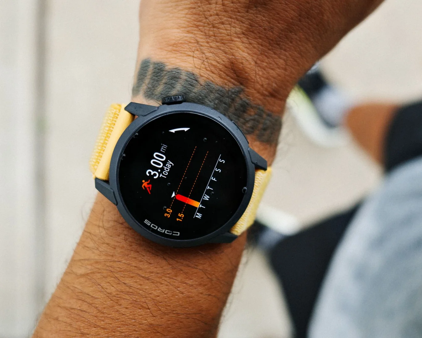 COROS GPS smartwatch on a tattooed wrist displaying activity tracking data during a run