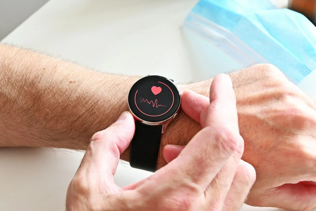 Person checking a smartwatch displaying a heart rate waveform on the screen