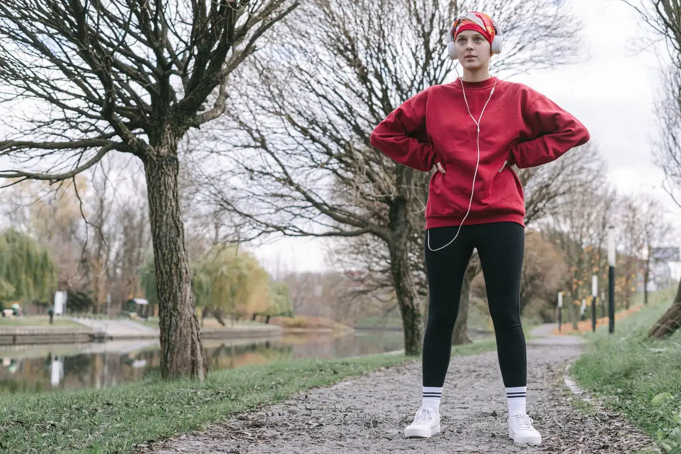Woman in red sweatshirt standing on a park path during a low-intensity outdoor run