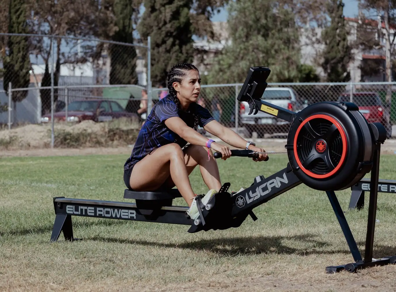 Athletic woman using an outdoor rowing machine on a grass field