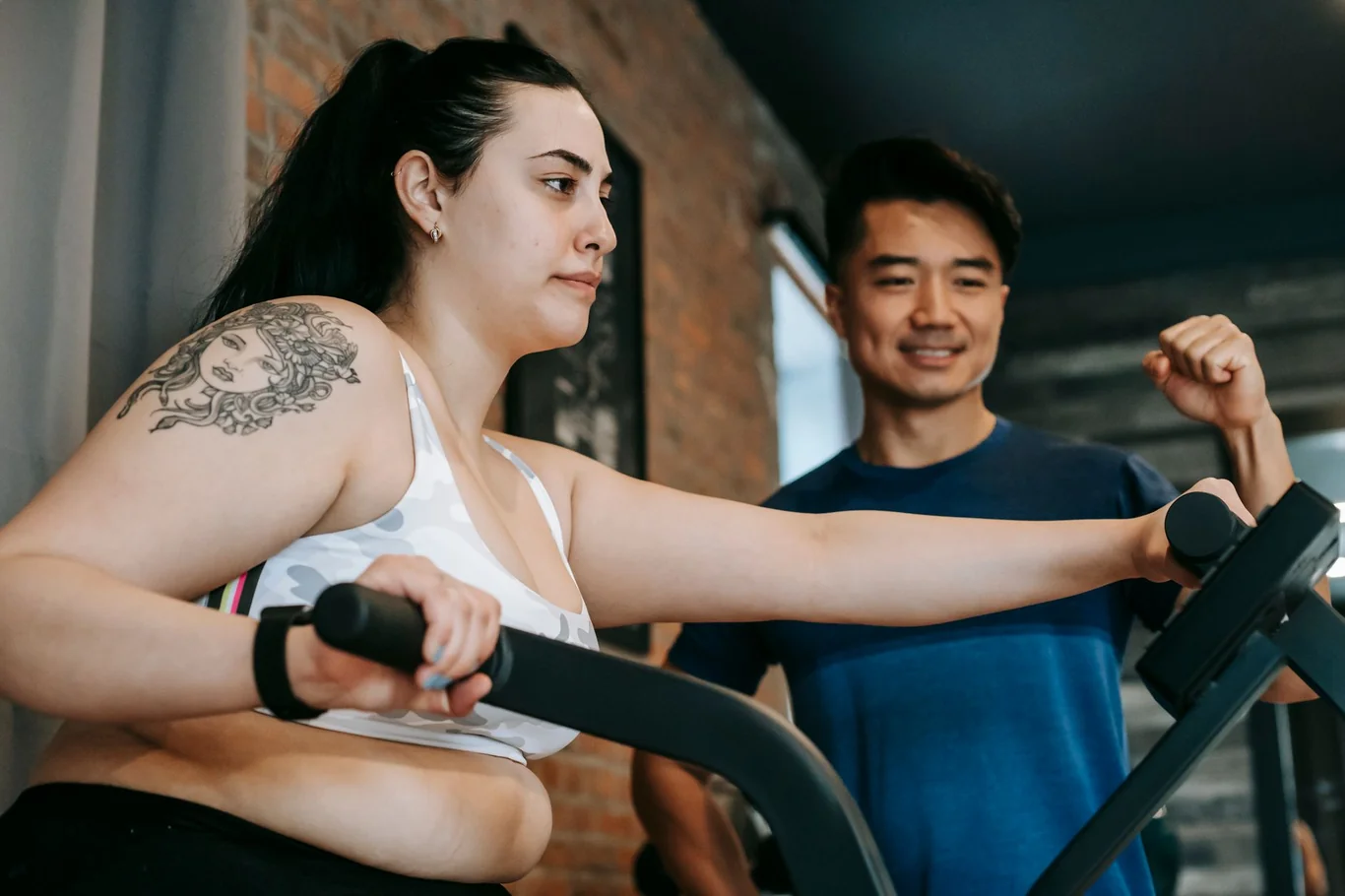 Two people working out on elliptical machines in a gym