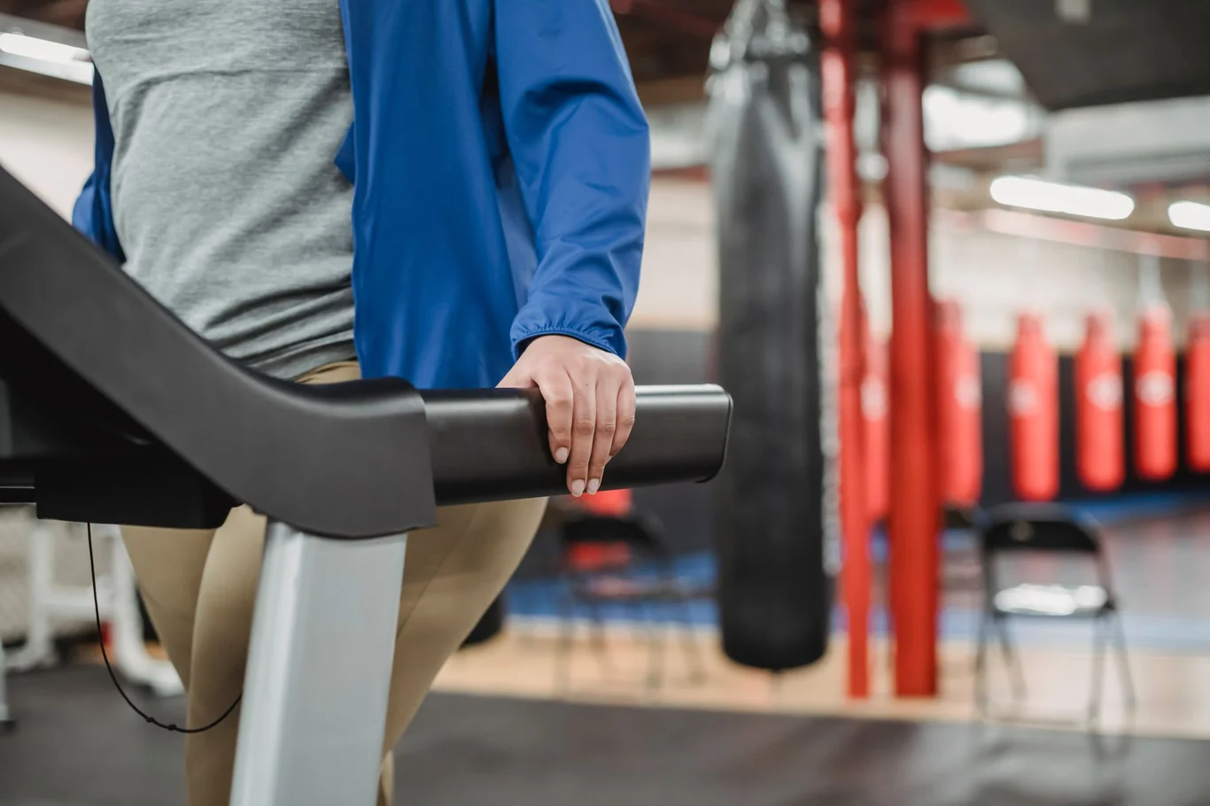 Person gripping the handlebars of a stair climber machine in a gym