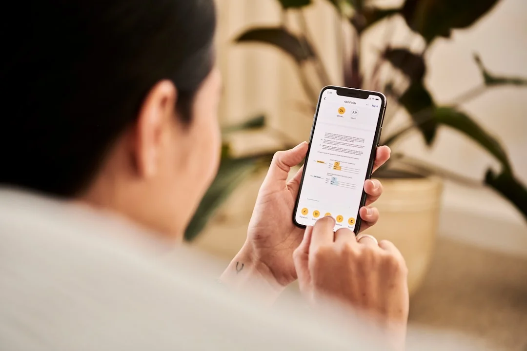 Person seated at home checking a wellness app on a smartphone near a potted plant