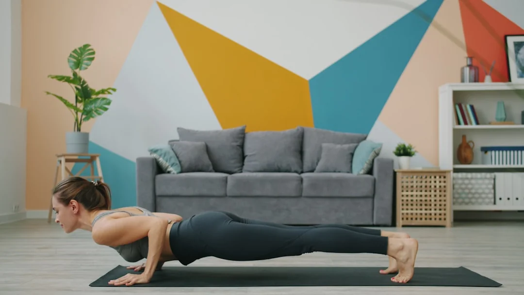 Woman holding a plank position on a mat in a bright modern living room