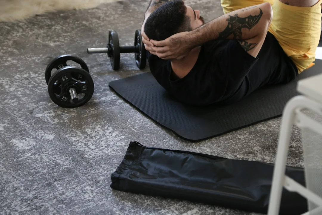 Man performing crunches on a mat with dumbbells on a concrete home gym floor