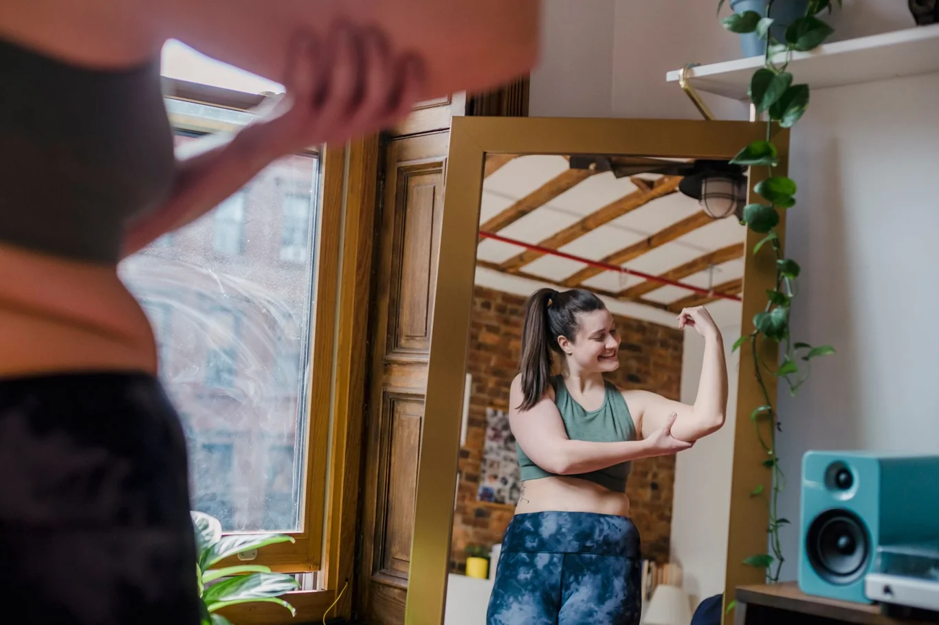 Woman flexing her bicep while checking her reflection in a home mirror