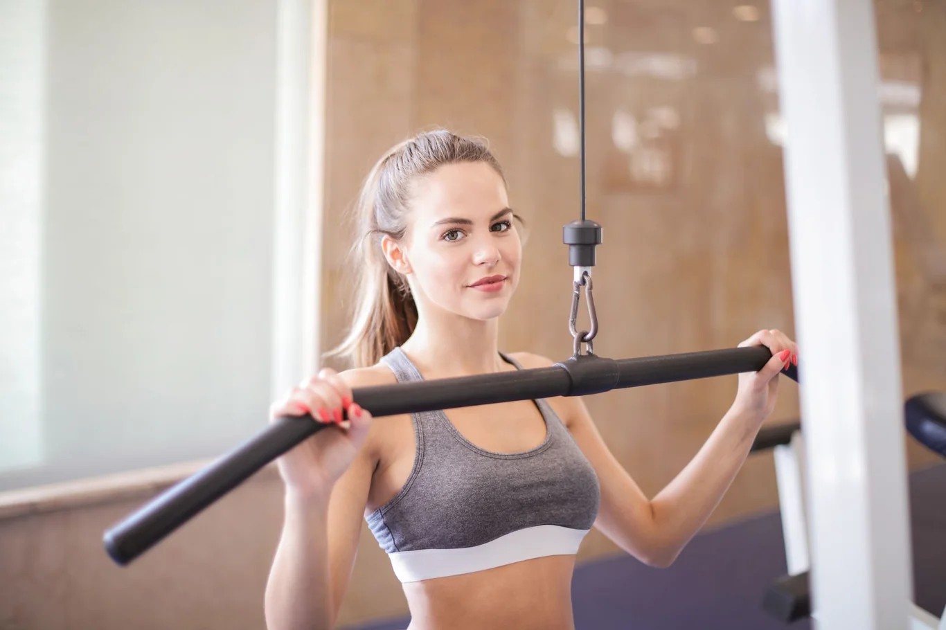 Woman gripping a cable pulldown bar during a strength training exercise