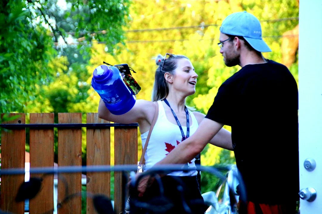 Woman holding a blue water bottle while chatting with a training partner outdoors after a run