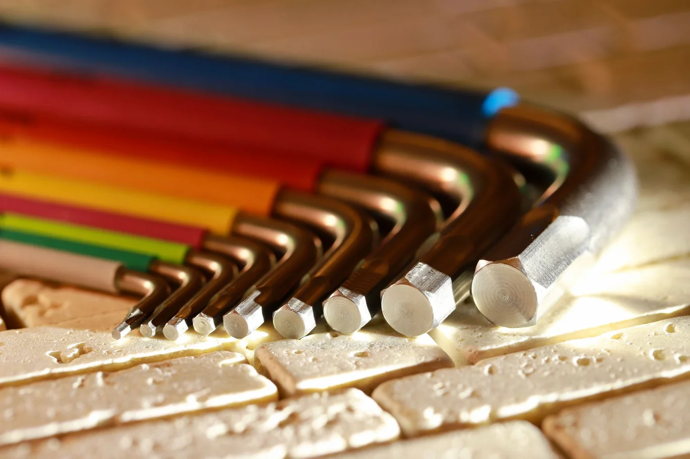 Set of colorful L-shaped allen wrenches arranged by size on a stone surface
