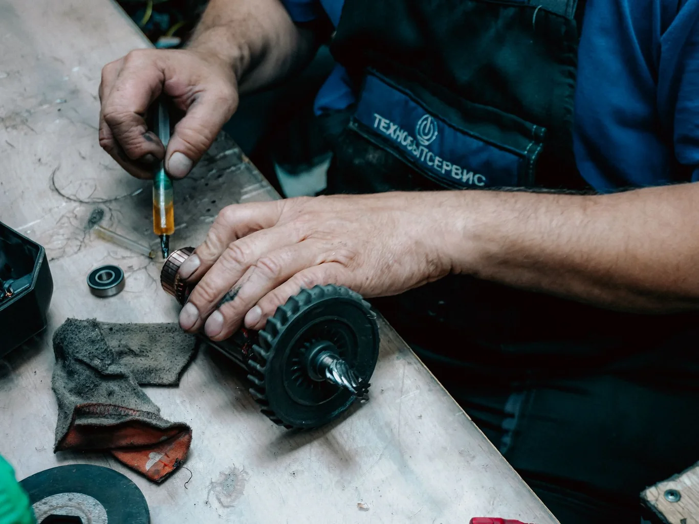 Technician in a service uniform repairing a mechanical gear component on a workbench