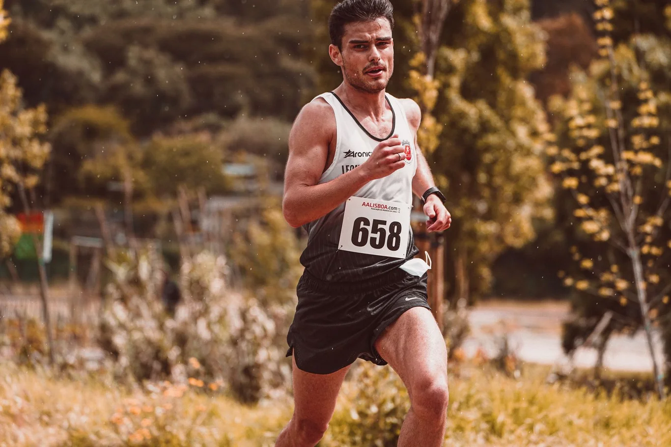 Male runner pushing hard on an outdoor trail course with intense effort on his face