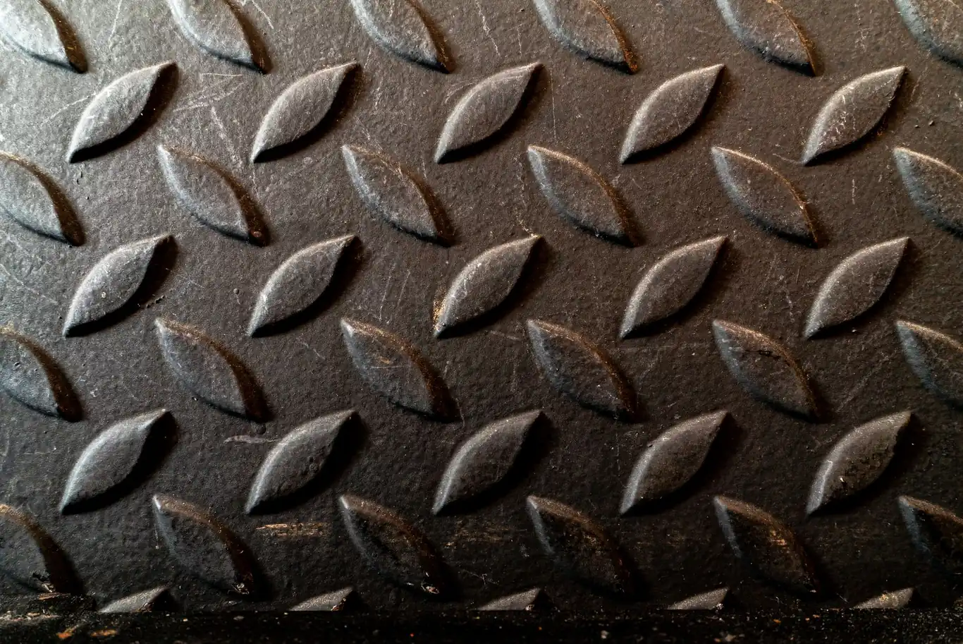 Close-up of a dark textured non-slip surface with raised oval studs in a grid pattern