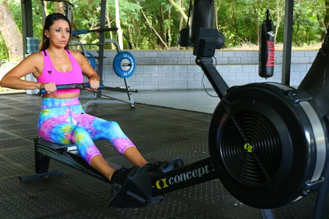 Woman rowing on a Concept2 ergometer in an outdoor gym setting