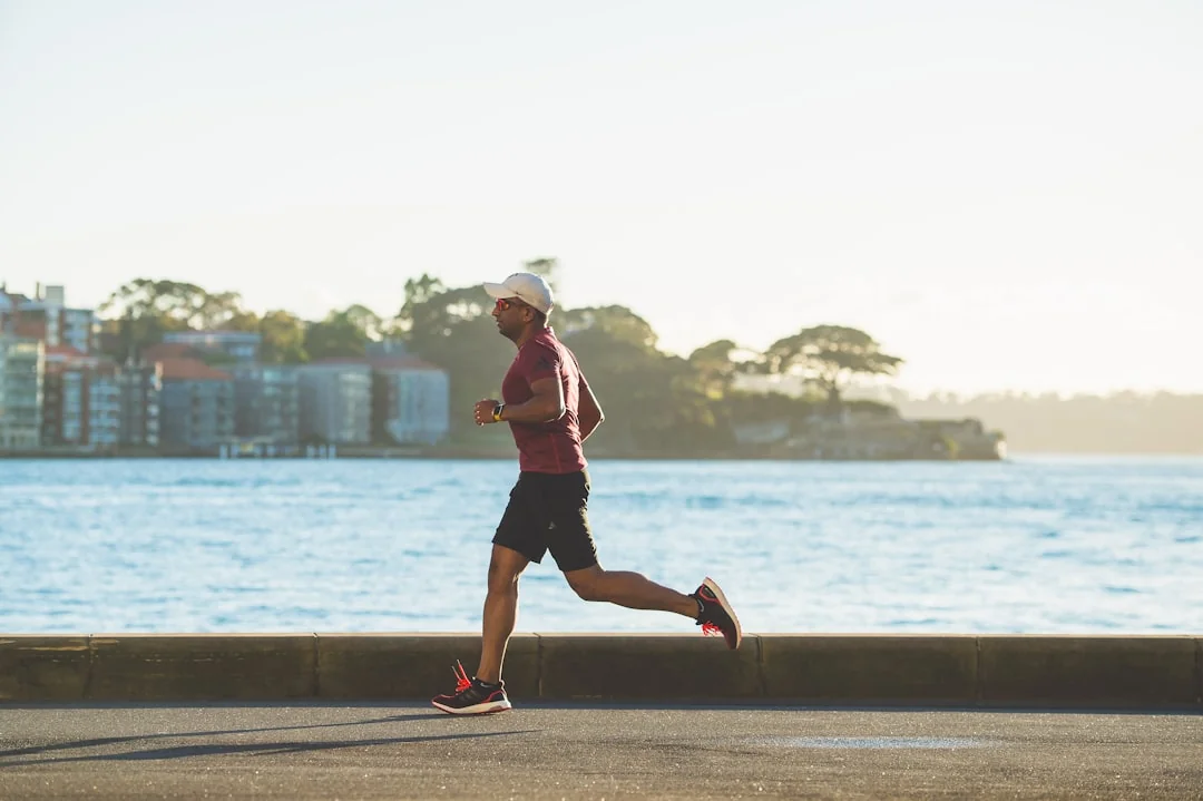 Man jogging at an easy pace along a waterfront path in soft natural light