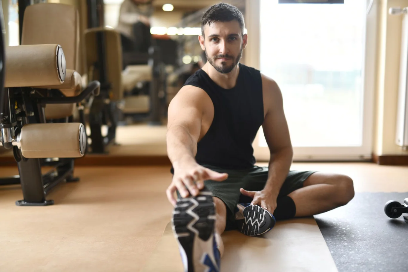 Man stretching on gym floor with fitness equipment in background