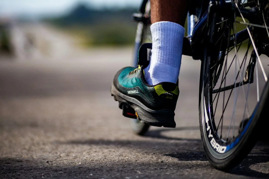 Close-up of a cyclist's foot on a pedal while riding on an open road