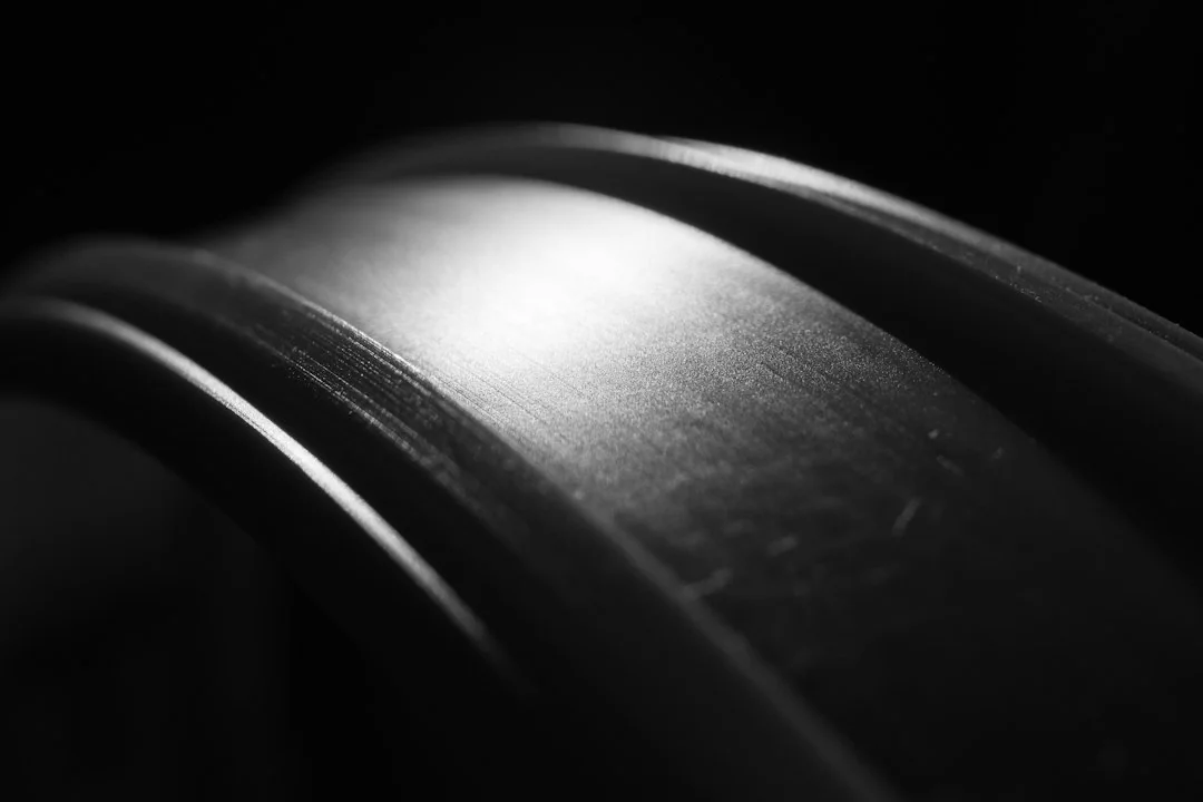 Close-up of a smooth curved belt surface with dramatic lighting revealing texture and surface wear