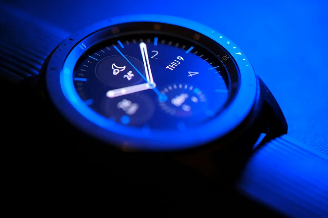 Galaxy Watch with illuminated blue bezel resting on a dark surface