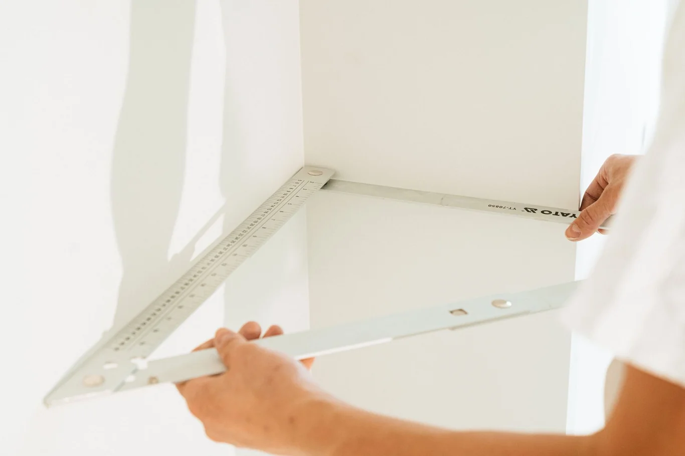 Person using a square ruler to measure a room corner for home gym planning