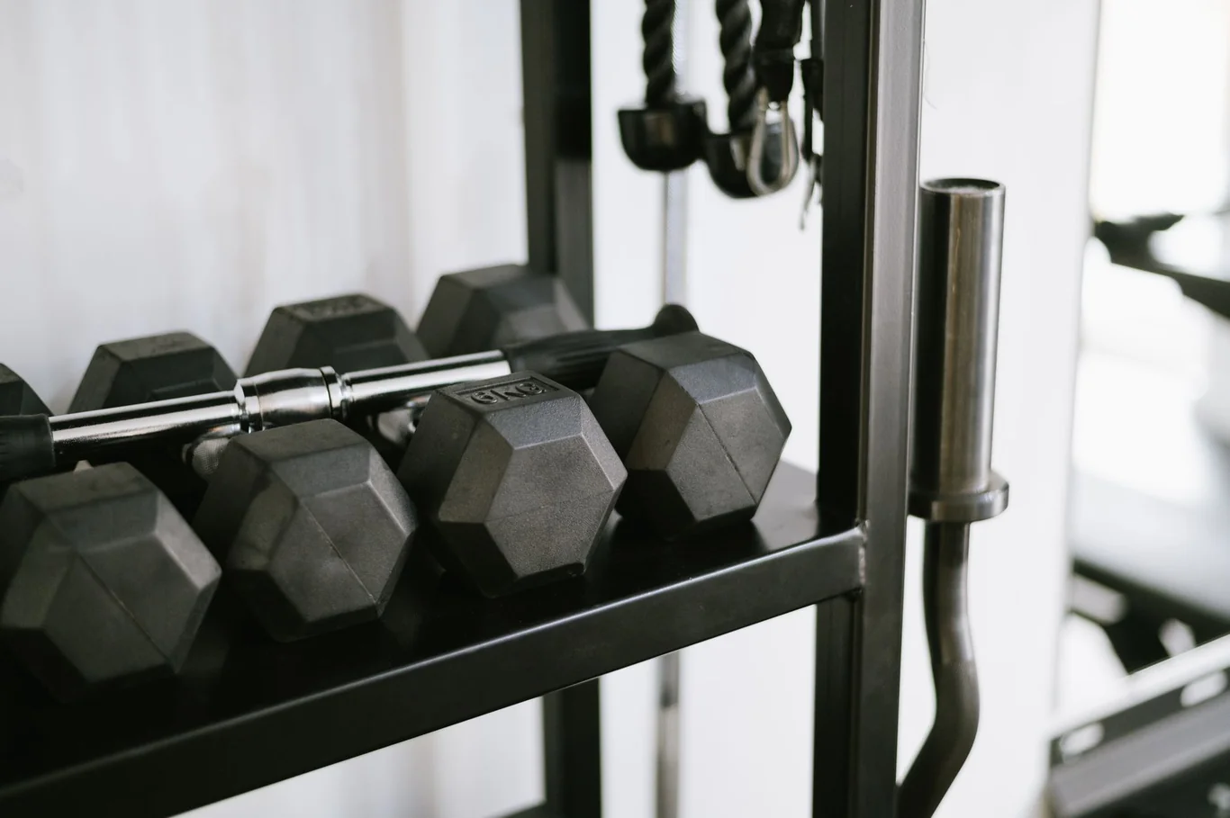 Hex dumbbells organized on a black rack in a clean home gym space