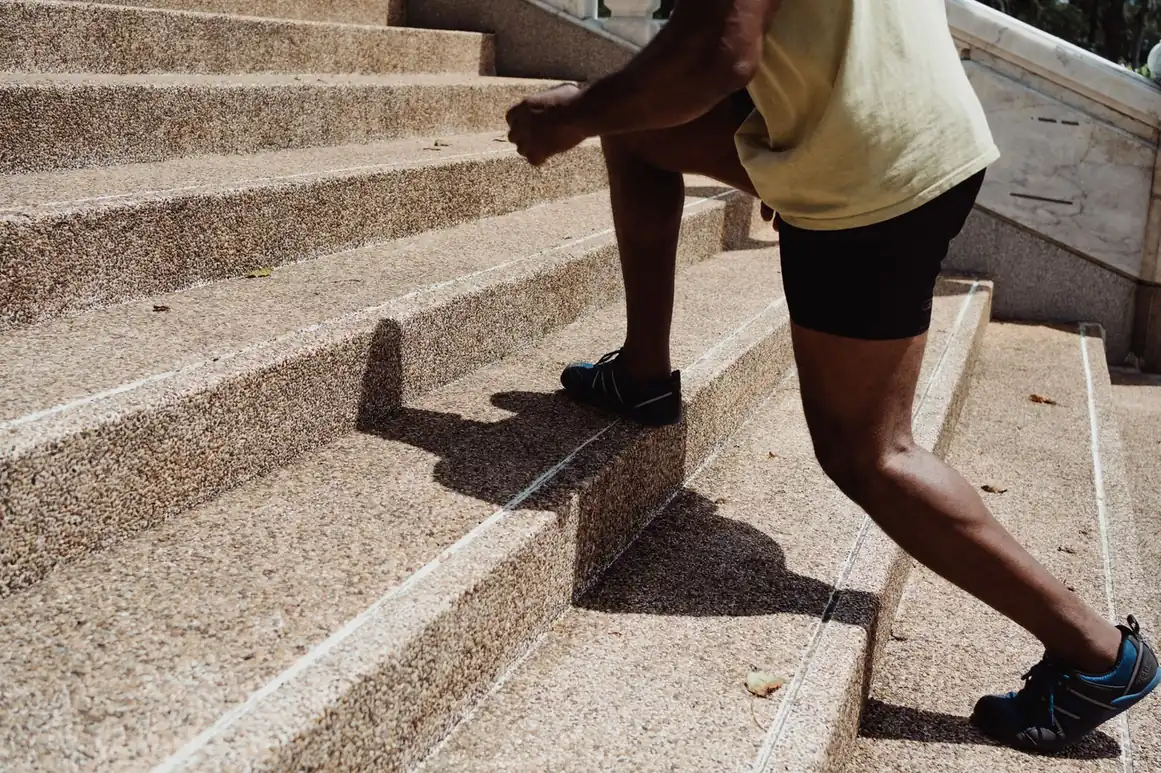 Athlete climbing stone stairs with a high-knee stride showing lower-body engagement