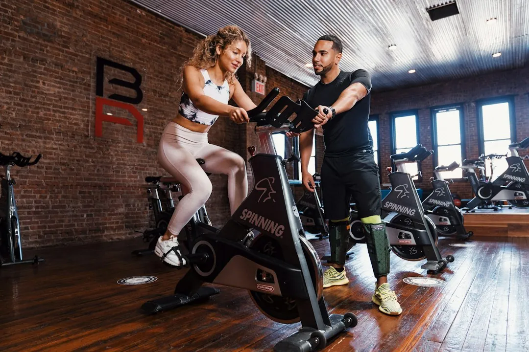 Woman riding a spin bike during a workout session with an instructor in a cycling studio