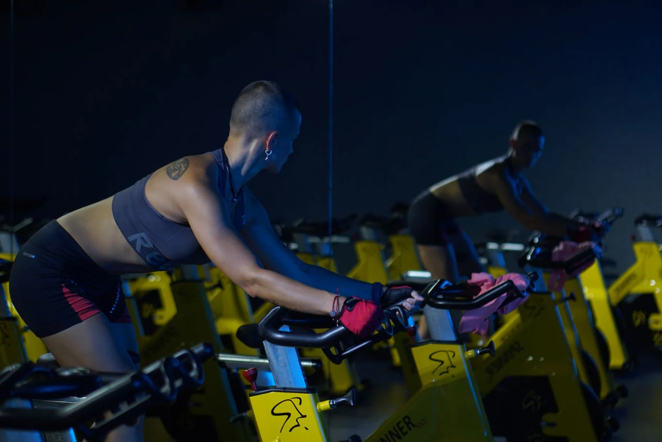 Woman riding a yellow spin bike in an intense HIIT workout at an indoor cycling studio