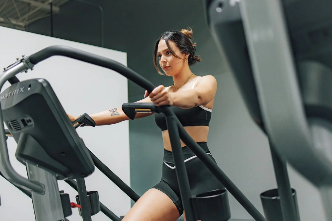 Woman gripping handlebars working out intensely on a cardio climbing machine in a gym