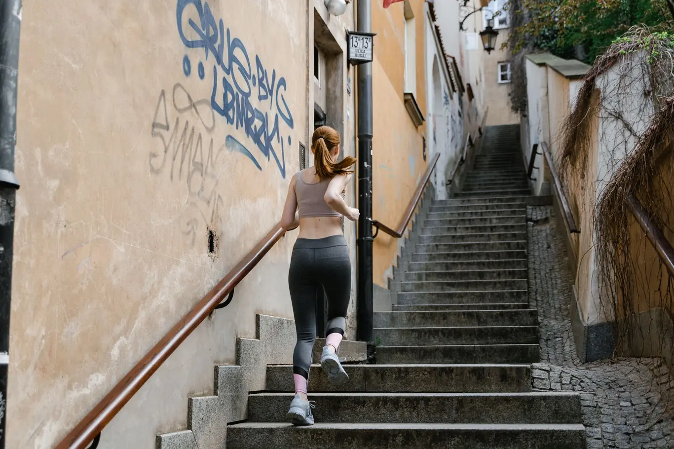 Woman in athletic wear running up outdoor stone stairs during a cardio workout