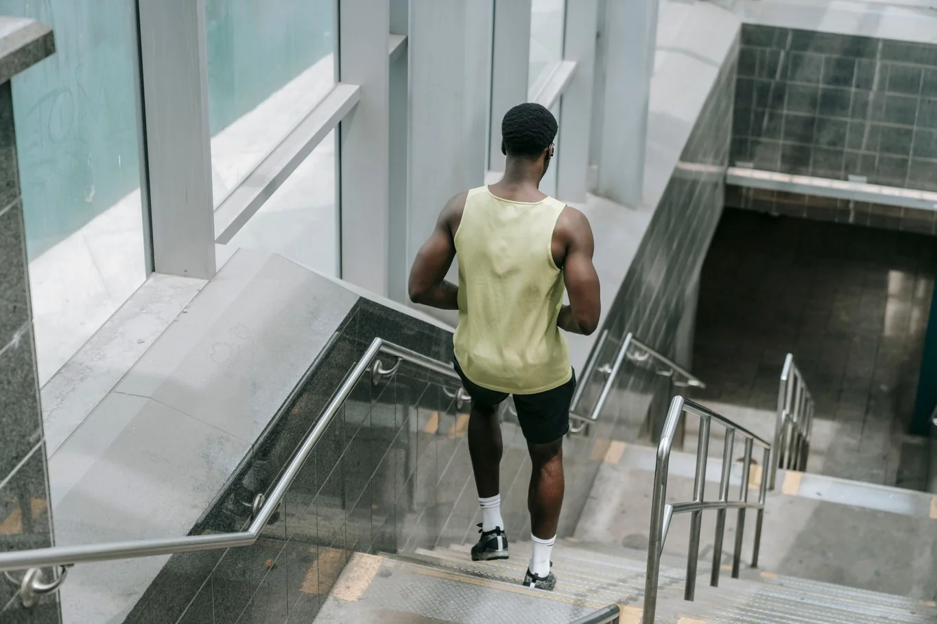 Athletic man in a yellow tank top running up stairs during an intense cardio workout