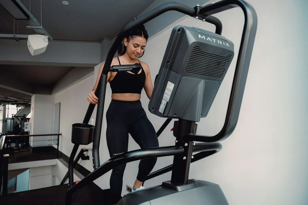 Woman in black athletic wear stepping on a Matrix stair climber machine in a gym