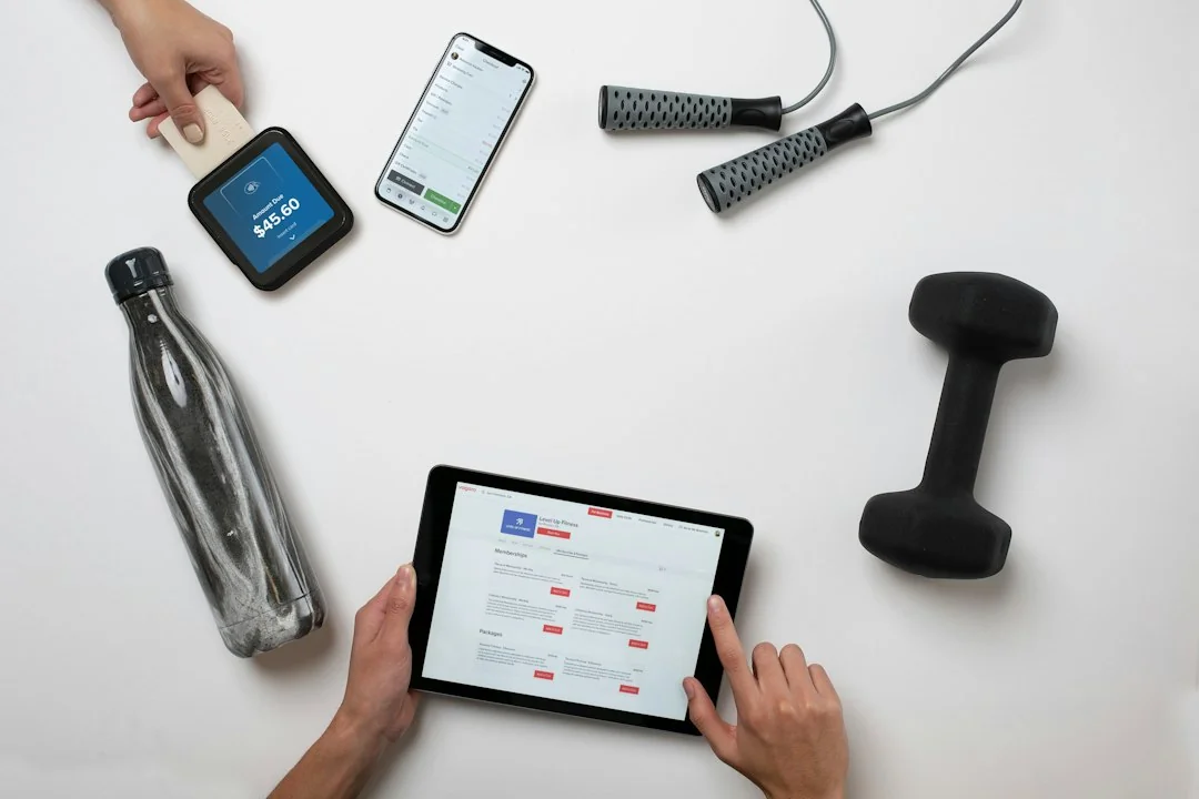 Person using a tablet to compare fitness equipment options, with a water bottle, jump rope, and dumbbell nearby