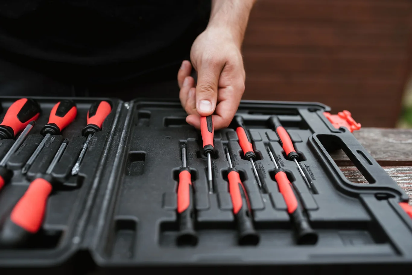 Hand selecting a red-handled screwdriver from an open tool kit for equipment maintenance