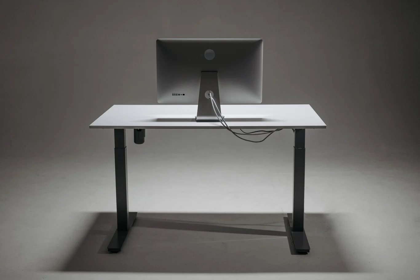 Height-adjustable standing desk with white top and dark metal frame supporting a desktop monitor