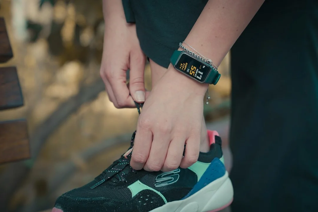 Fitness tracker band on wrist while person ties running shoe